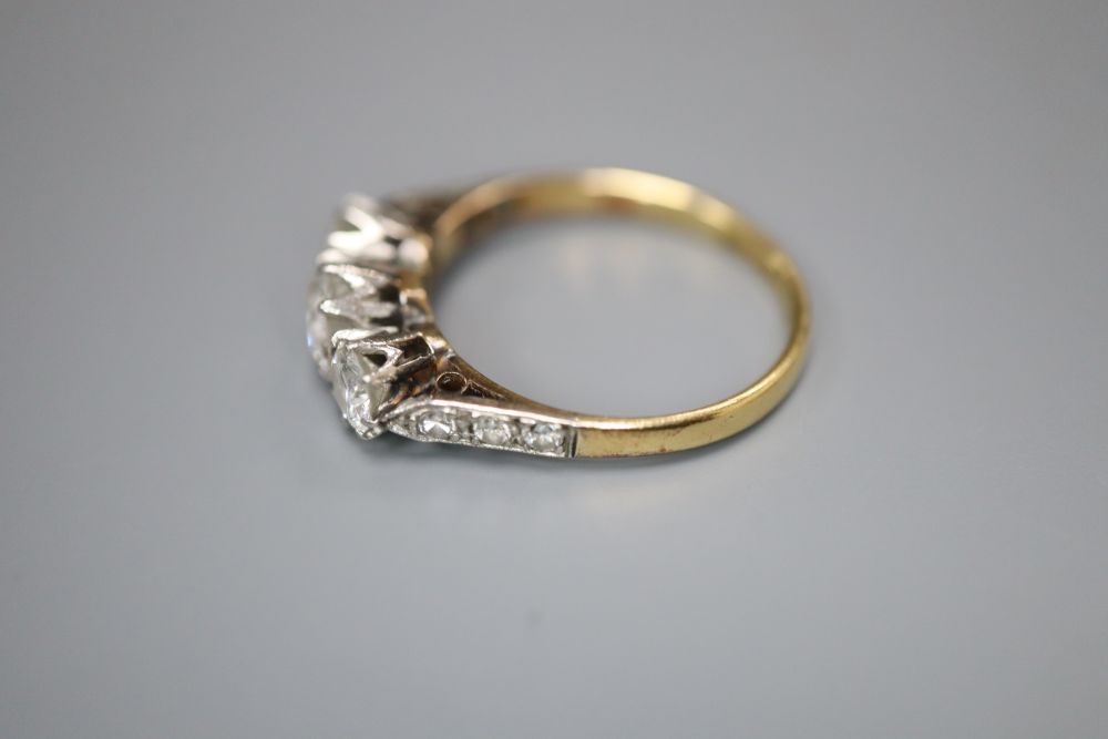 A mid 20th century 18ct and plat three stone diamond ring, with diamond set shoulders, size K/L, gross 2.4 grams.